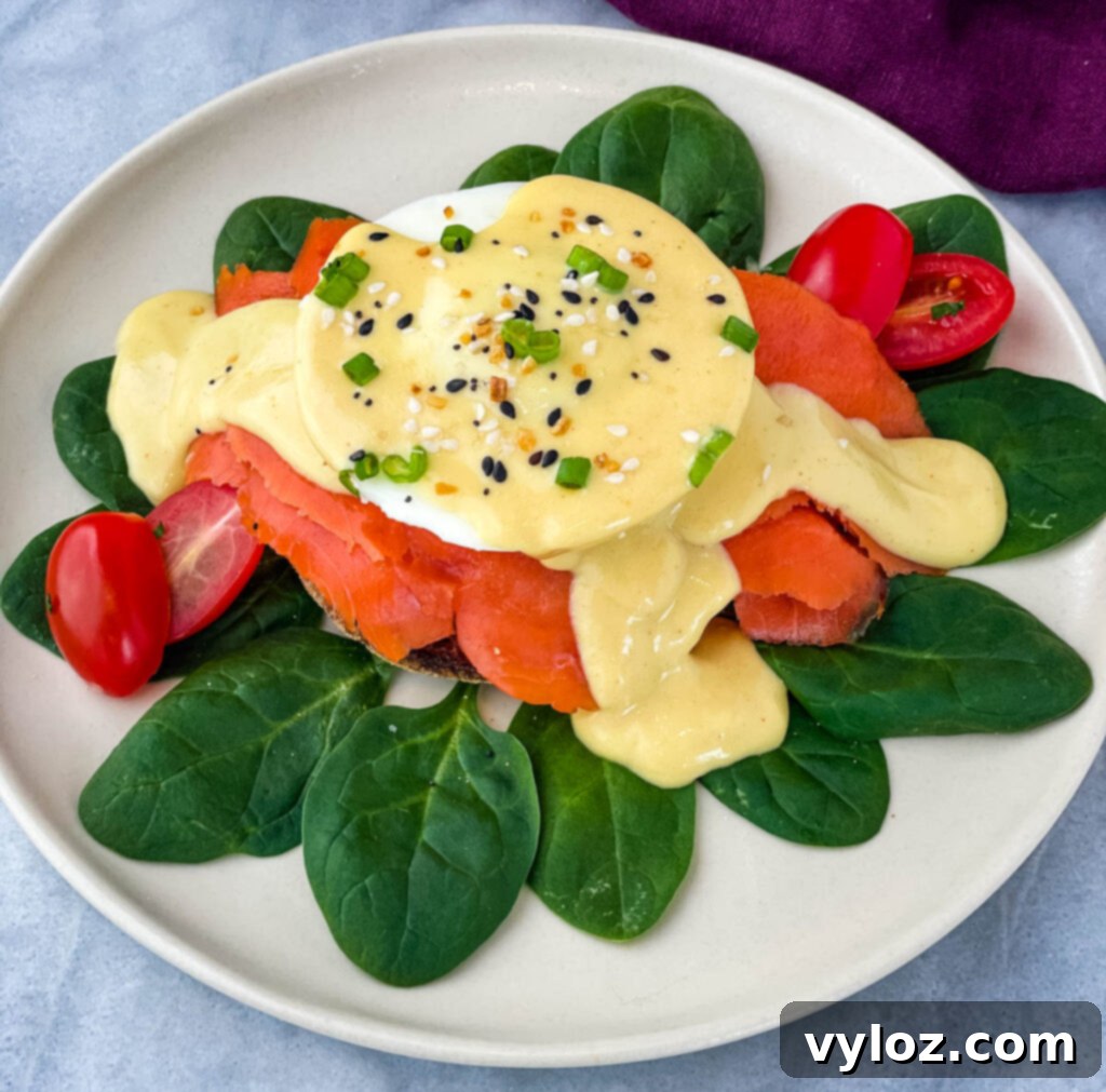 Smoked Salmon Eggs Benedict on a bed of spinach, garnished with fresh herbs