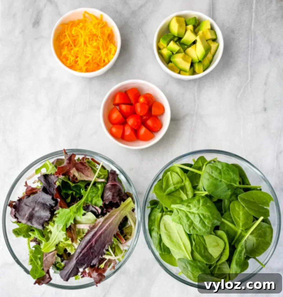 salad greens, spinach, tomatoes, cheddar cheese, avocados, and tomatoes in separate bowls