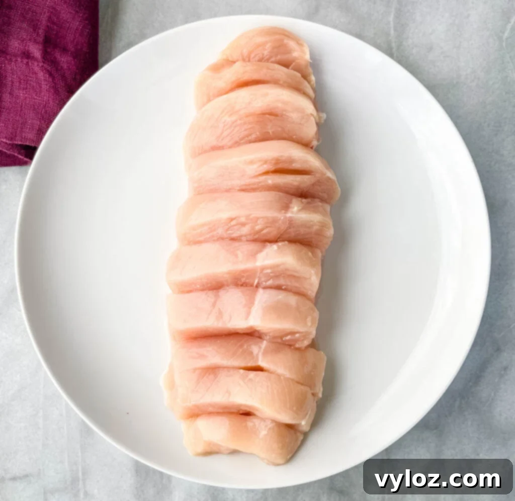 raw sliced chicken breast on a white plate
