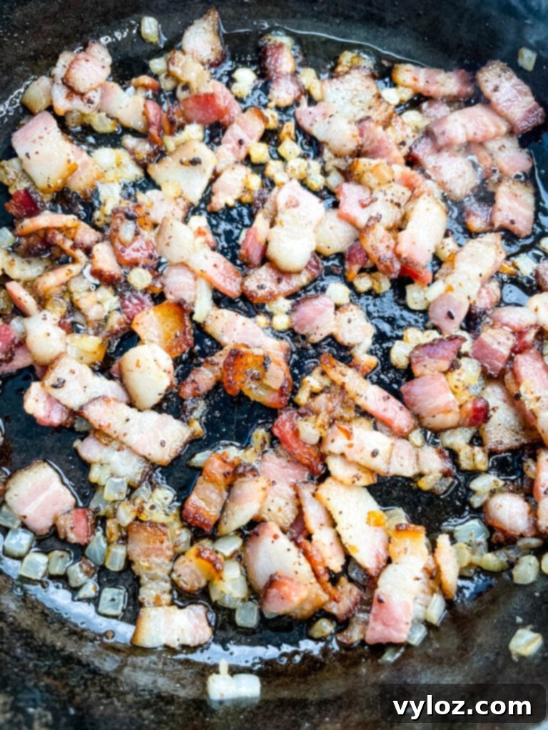 cooked bacon and onions in a cast iron skillet