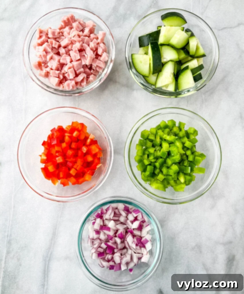 chopped ham, cucumbers, red peppers, green peppers, and red onions in separate bowls