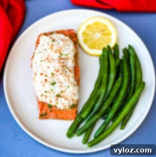 crab stuffed salmon on a white plate with green beans as a side dish.