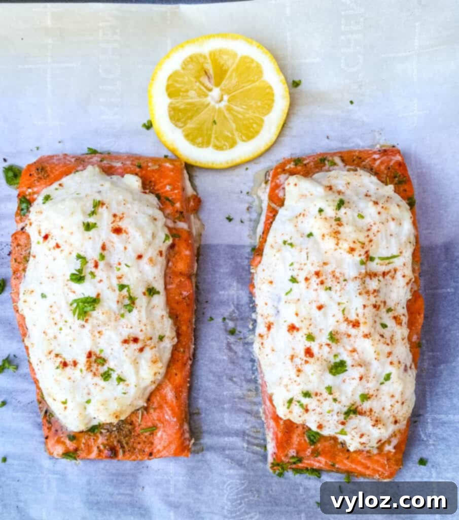 Crab stuffed salmon garnished with fresh lemon slices on parchment paper.