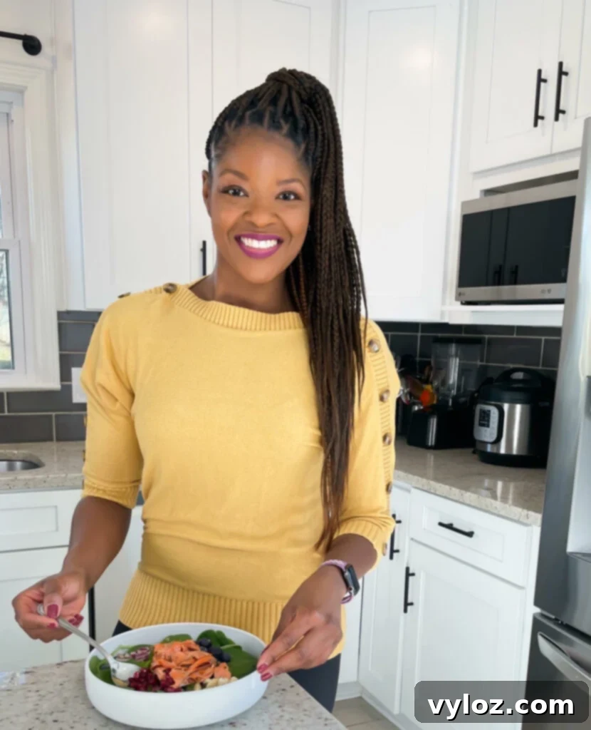 A person stands confidently in a modern kitchen, holding a bowl of food, symbolizing culinary creativity and home-based entrepreneurship.