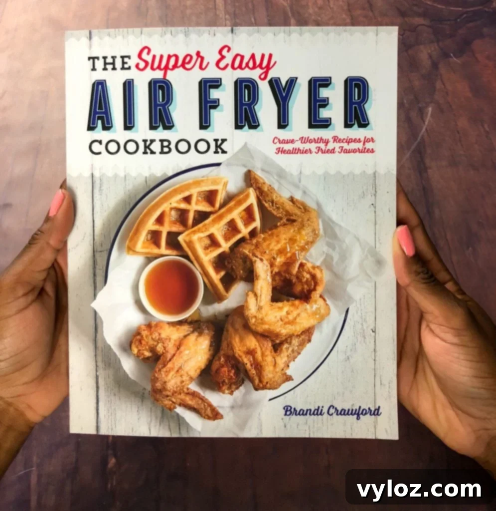 A person proudly holds up 'The Super Easy Air Fryer Cookbook,' a testament to the author's expertise and success in the air frying community.