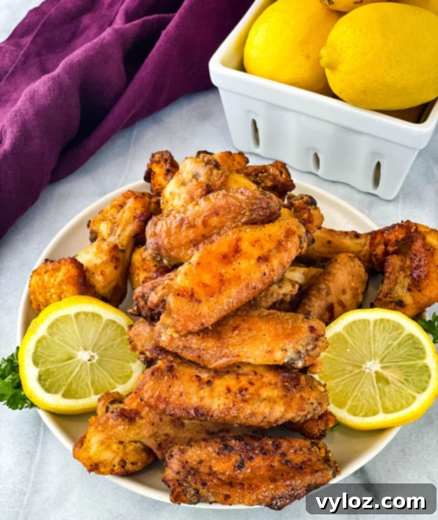 Crispy lemon pepper chicken wings on a plate with fresh lemon slices, ready to be served