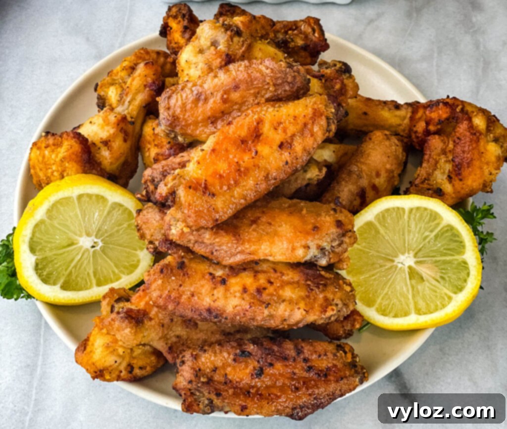 A close-up shot of glistening lemon pepper chicken wings on a plate, highlighting their crispy skin and rich glaze