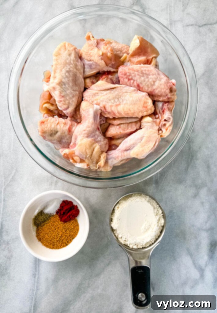 Raw chicken wings, separated into drumettes and flats, ready for seasoning in a clear glass bowl