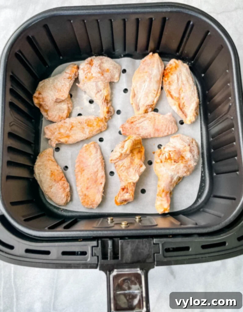 Crispy raw breaded chicken wings nestled in an air fryer basket, perfectly spaced for even cooking
