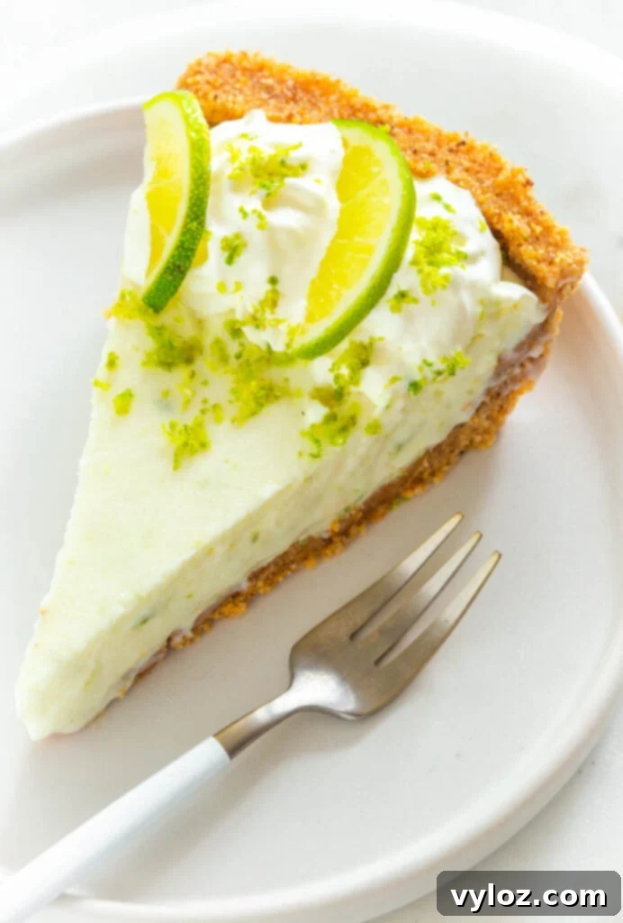Guilt-Free Key Lime Bliss 12 A perfect slice of keto low carb key lime pie on a white plate with fresh limes and a fork, ready to be enjoyed.