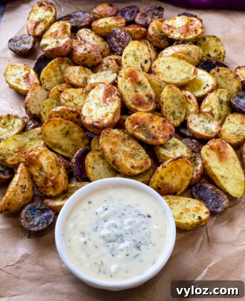 Crispy Ranch Roasted Potatoes 12 A serving of roasted ranch potatoes on a white plate, accompanied by a small bowl of ranch dressing