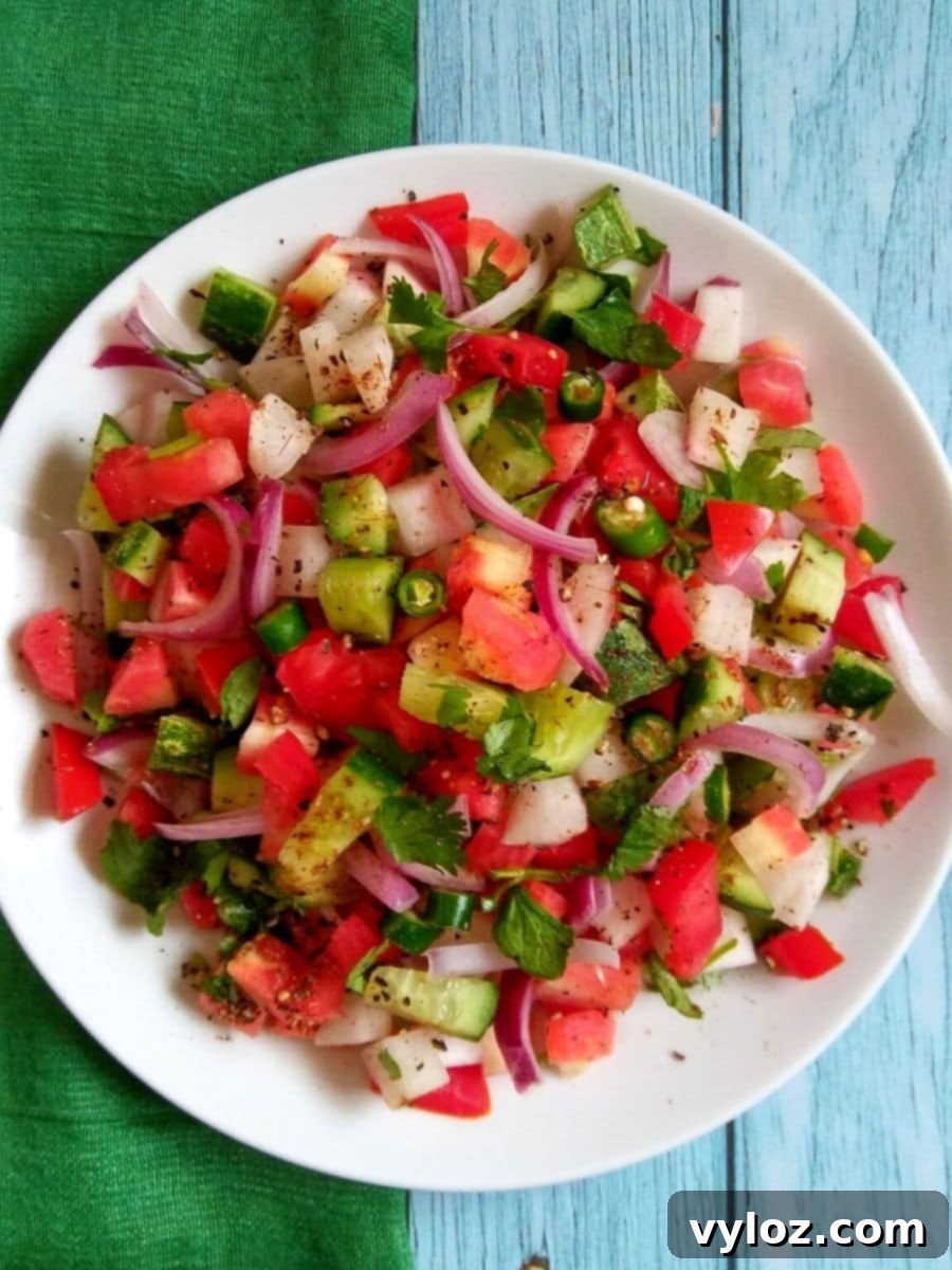 Freshly prepared Kachumber salad served in a white bowl, showcasing vibrant diced cucumbers, tomatoes, and onions.