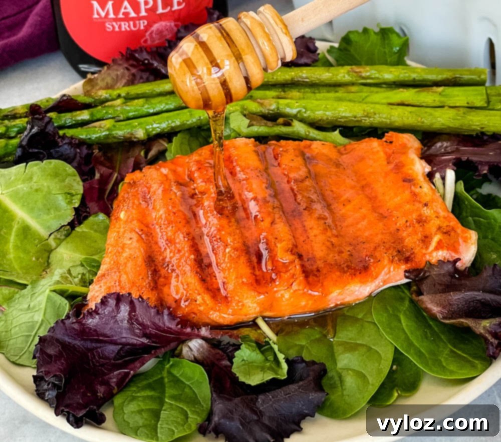 Sweet and Simple Maple Salmon 2 maple glazed salmon drizzled in syrup on a plate with asparagus and mixed greens