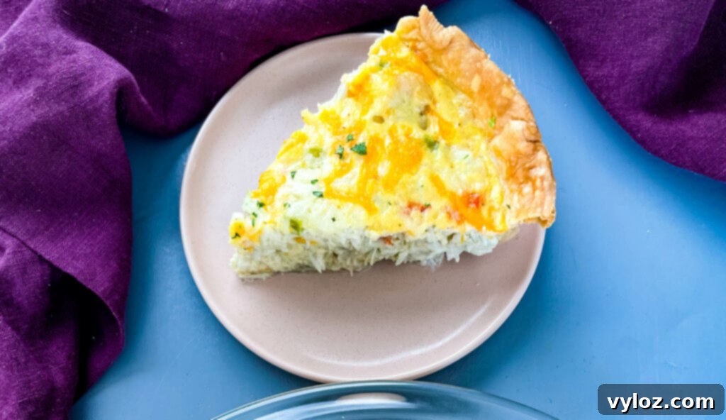 A close-up shot of a single slice of shrimp and crab quiche on a plate, highlighting its rich filling and textures.