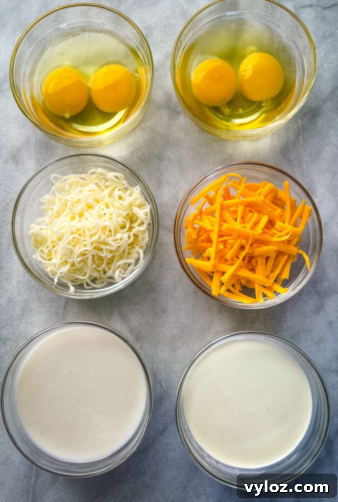 Bowls containing raw eggs, shredded cheese, almond milk, and heavy cream, key ingredients for the quiche custard.