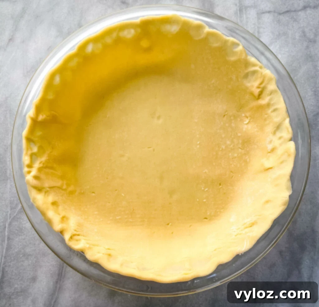 An unbaked pie crust expertly placed in a pie plate, ready for blind baking.