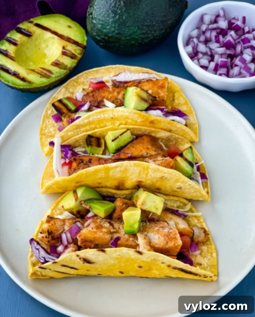 Blackened Fish Tacos on a plate with fresh avocado and cabbage