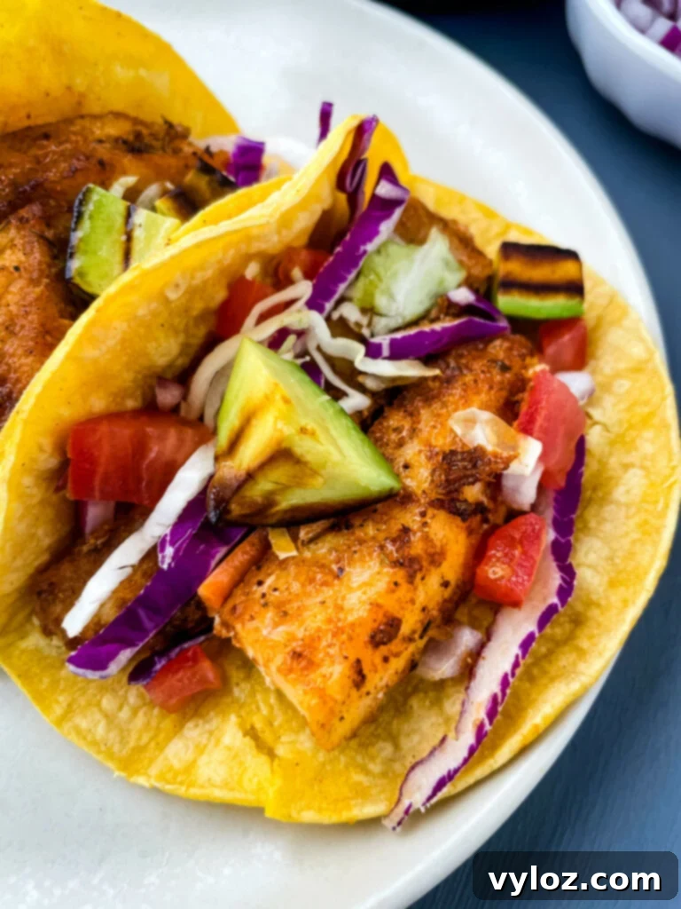 Blackened Fish Tacos on a plate with fresh avocado and cabbage