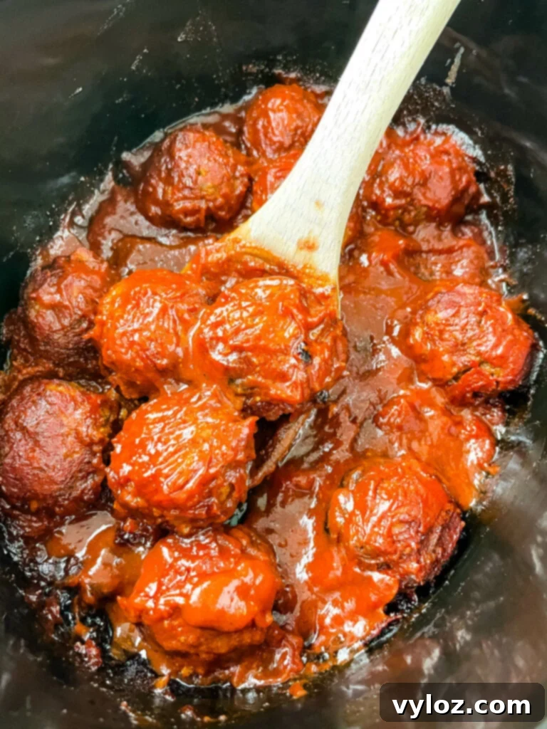 Set-It-and-Forget-It BBQ Meatballs 11 BBQ meatballs in a slow cooker, close up shot with steam
