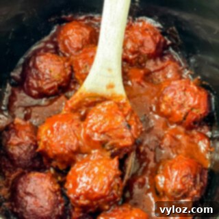 Set-It-and-Forget-It BBQ Meatballs 12 BBQ meatballs in a slow cooker with a wooden spoon