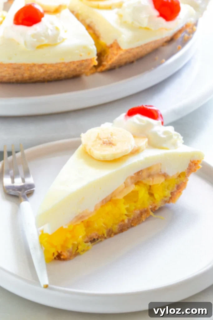 A whole banana split pie in a pie plate, with whipped cream and cherries, waiting to be served.