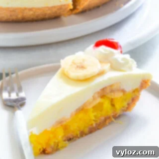 A slice of No-Bake Banana Split Pie on a white plate, topped with whipped cream, a maraschino cherry, and a drizzle of chocolate syrup.