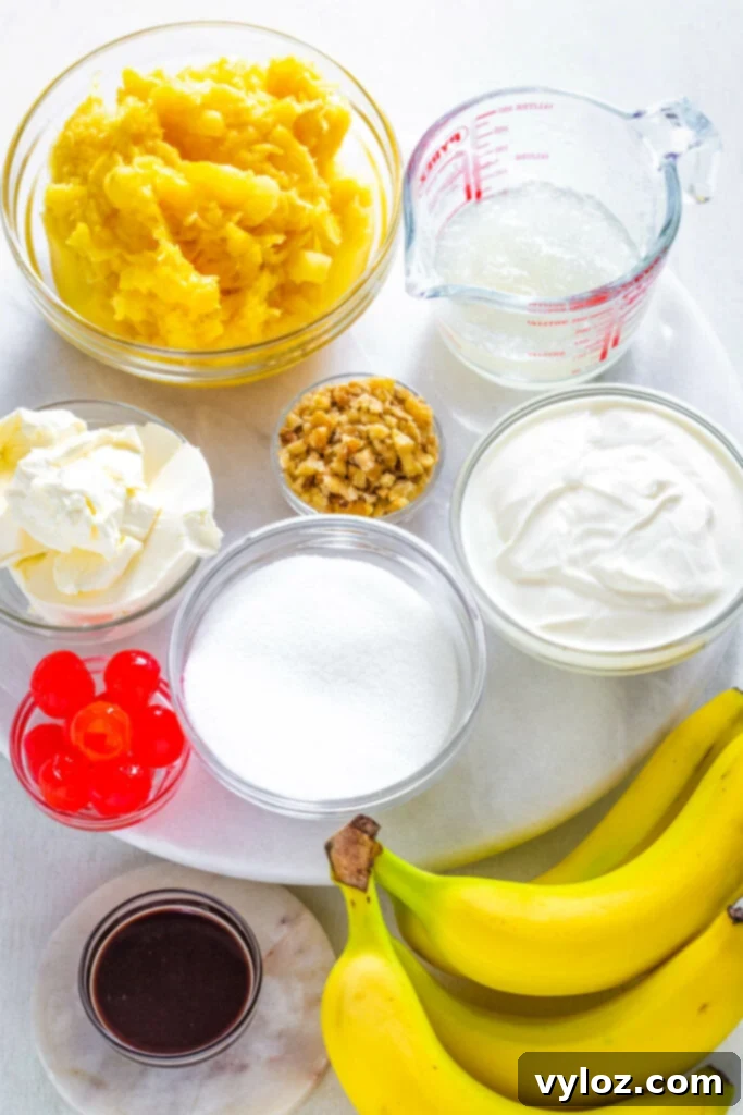 Separate bowls containing key ingredients: crushed pineapple, maraschino cherries, sliced bananas, Greek yogurt, cream cheese, and a bowl of sweetener, ready for pie assembly.