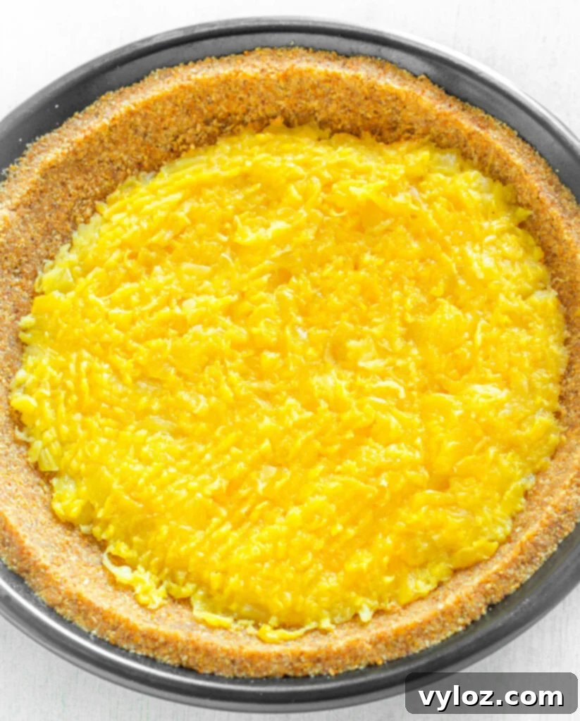 A pie plate with a prepared crust, layered with pineapple and sliced bananas, ready for the creamy filling.