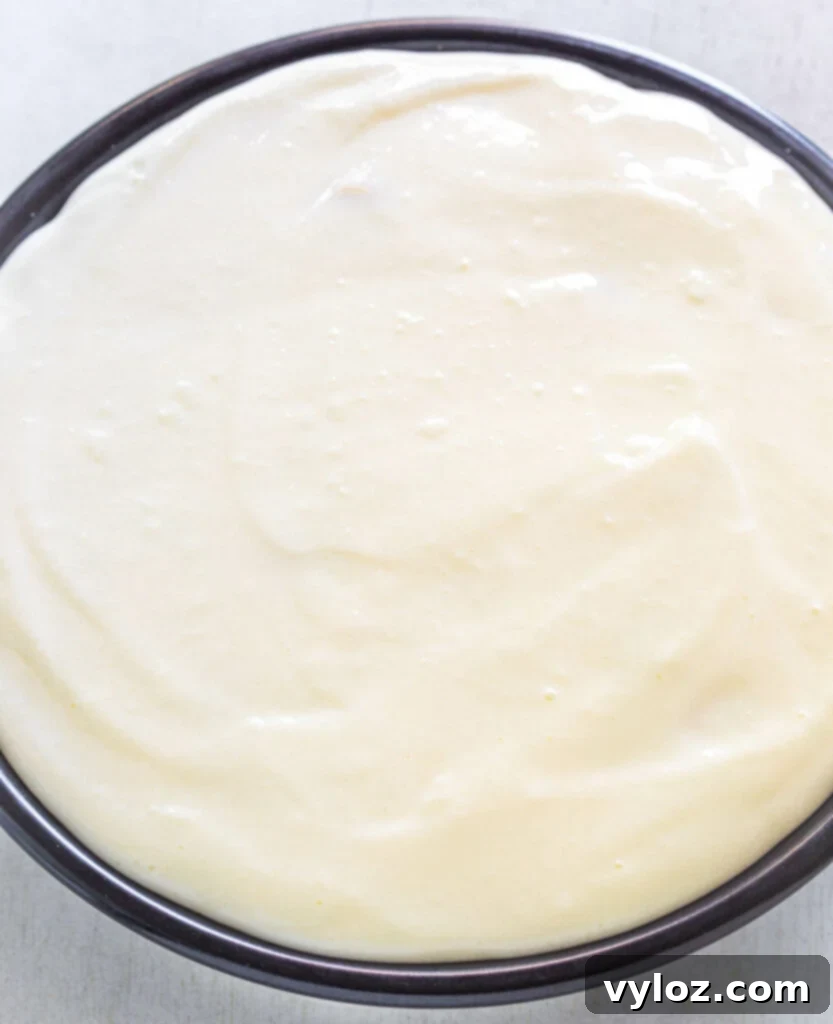 The creamy banana split pie filling poured into the crust and smoothed over the fruit layers, topped with bright red maraschino cherries.