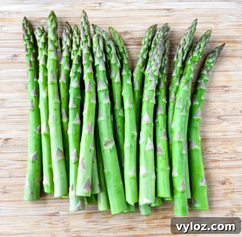 Grilled Asparagus Foil Packets 4 Trimmed raw asparagus spears laid out neatly on a wooden cutting board