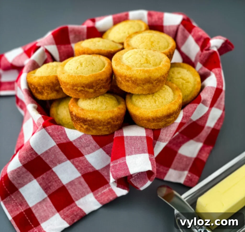 A basket full of golden-brown cornbread muffins, ready to be served.