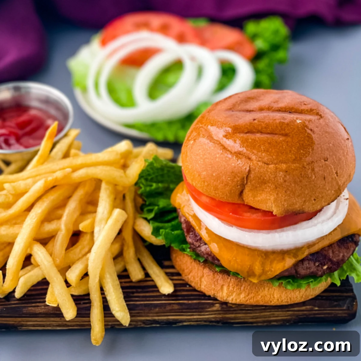 Achieve Burger Perfection on Any Grill 2 Grilled cheeseburgers on a bun with a plate of fries, showcasing a perfectly cooked, juicy burger
