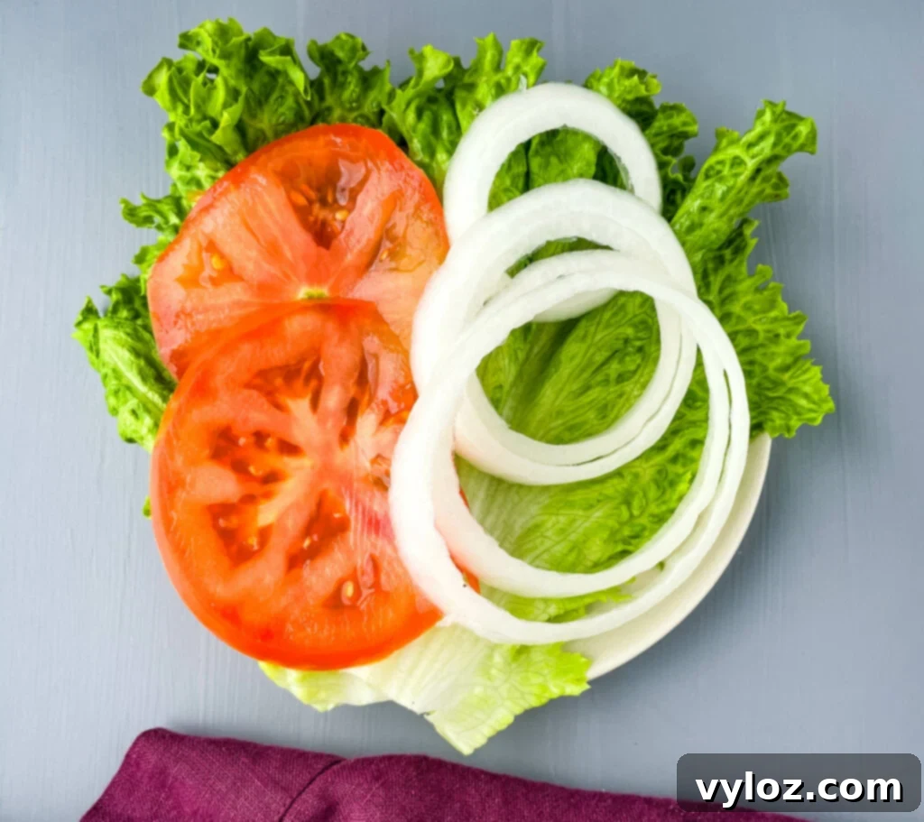 Achieve Burger Perfection on Any Grill 10 Lettuce, sliced tomatoes, and sliced onions on a plate, arranged as fresh burger toppings