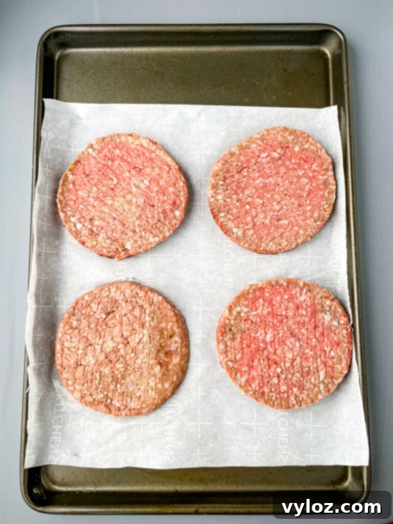 Savory Mushroom Swiss Burger 3 Raw, perfectly seasoned hamburger patties ready for cooking on a sheet pan.