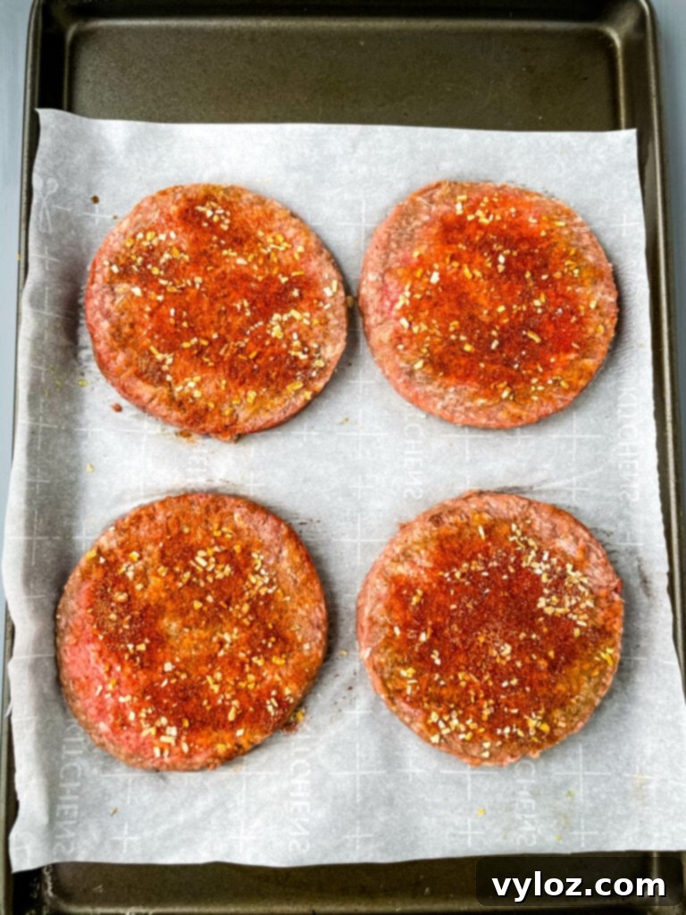 Savory Mushroom Swiss Burger 5 Raw, perfectly seasoned hamburger patties with thumb indents, arranged on a sheet pan, ready for grilling or air frying.