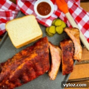baby back ribs on a plate with bread, BBQ sauce, and pickles