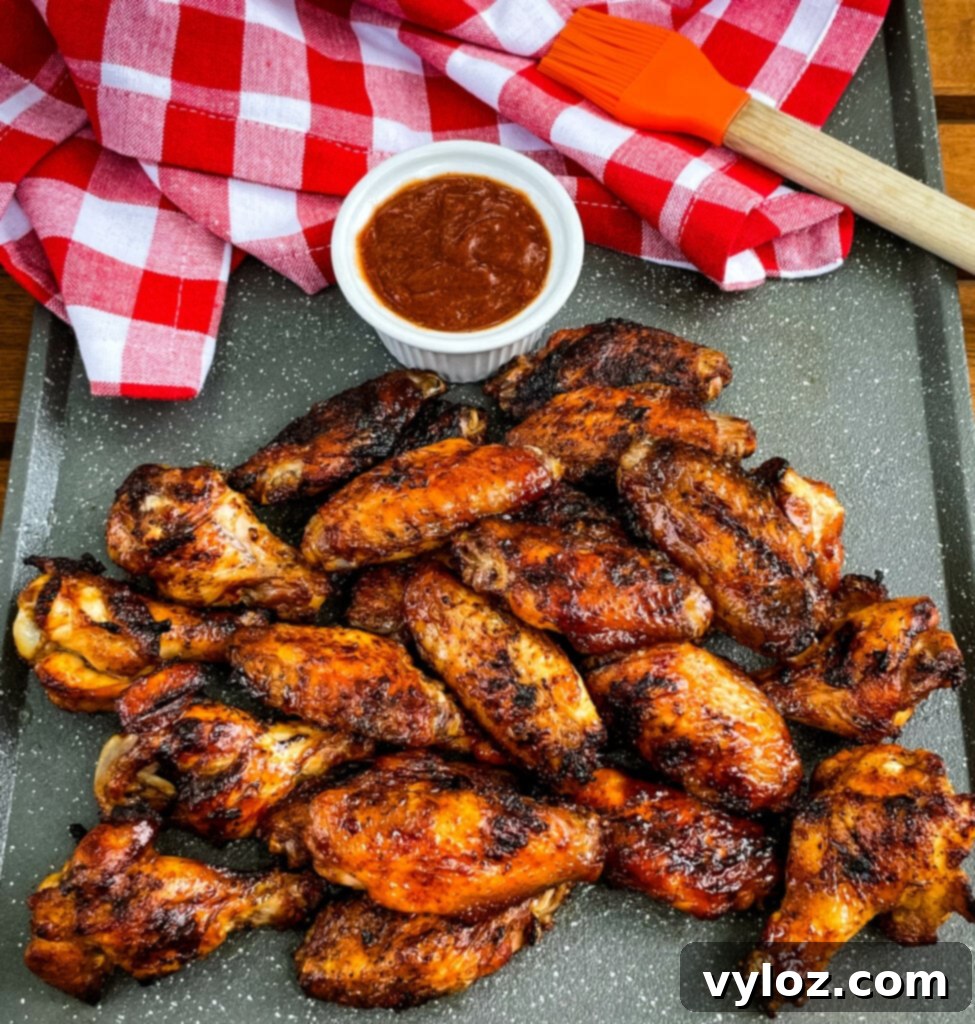 Perfect Grilled Chicken Wings 2 Grilled chicken wings on a plate with BBQ sauce, showcasing their crispy skin