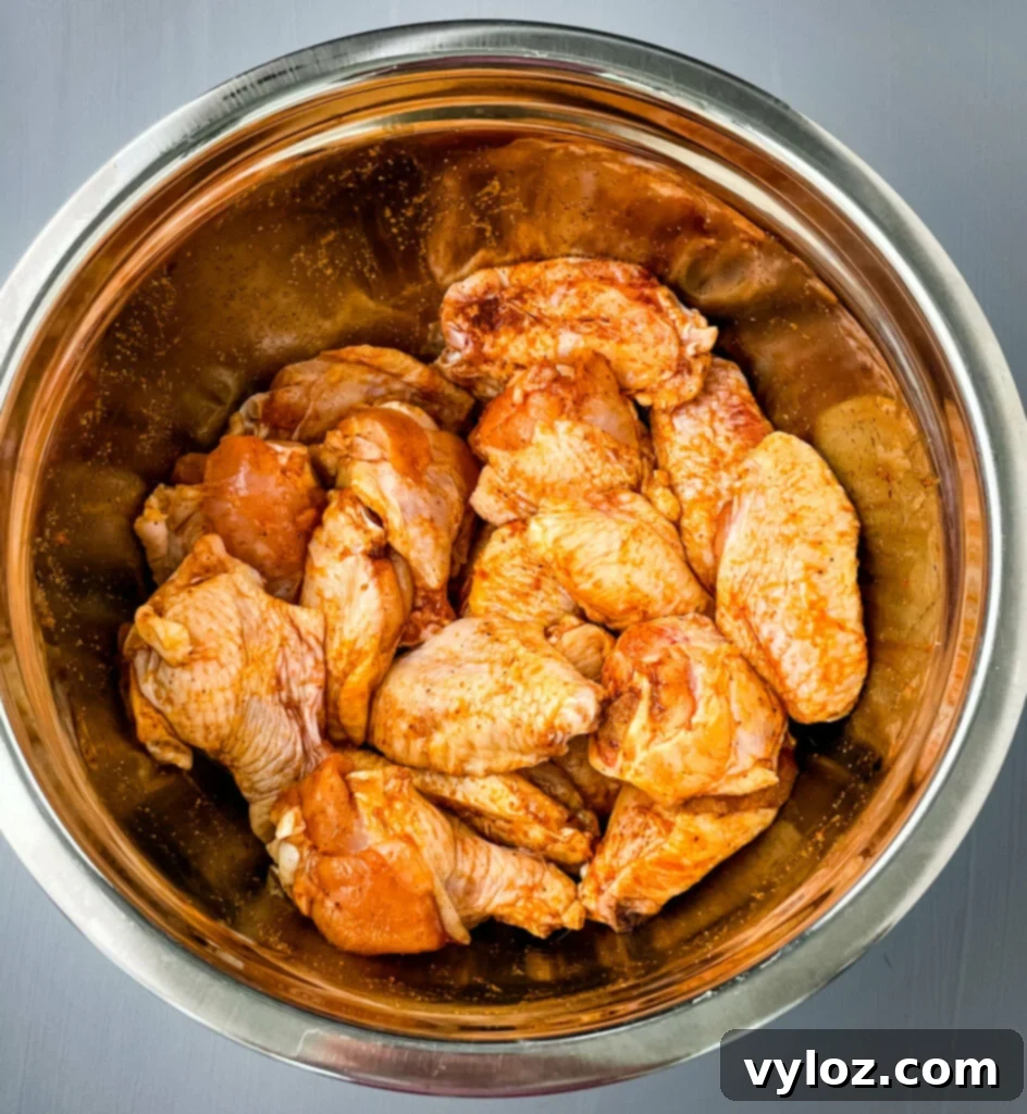 Perfect Grilled Chicken Wings 5 Raw chicken wings in a large bowl with seasoning and marinade