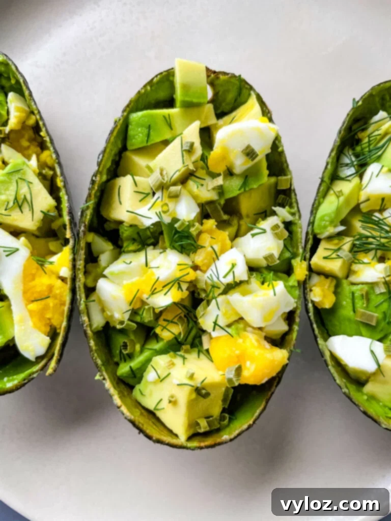 Savory Avocado Egg Bites 5 A selection of Avocado Egg Salad Cups garnished with fresh herbs, ready for serving.