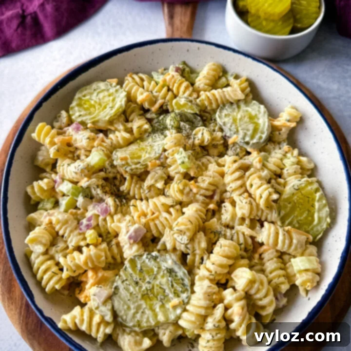 A creamy, tangy Dill Pickle Pasta Salad in a large serving bowl, generously loaded with chopped pickle pieces.
