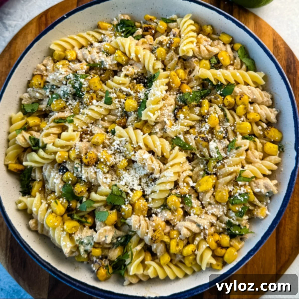 A vibrant Street Corn Pasta Salad, resembling authentic elote with crumbled cheese, fresh cilantro, and a creamy dressing, in a serving bowl.