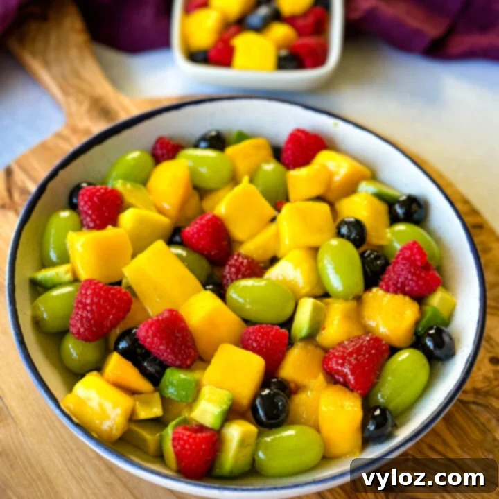 A delightful Mango Fruit Salad with a mix of sweet mangoes, various berries, juicy grapes, and sliced avocado, all glistening with a zesty honey-lime dressing.