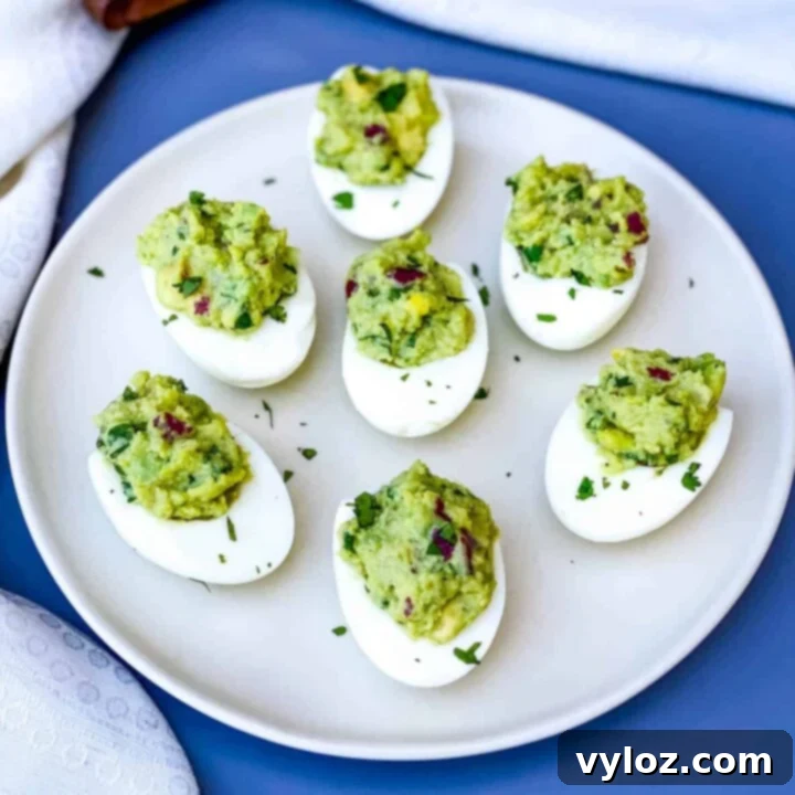 Creamy and vibrant Easy Avocado Deviled Eggs, beautifully garnished with crispy bacon bits and fresh cilantro.