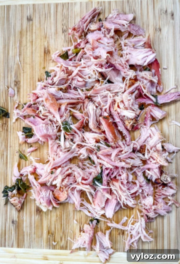 Shredded smoked turkey meat on a cutting board, prepared for collard greens.