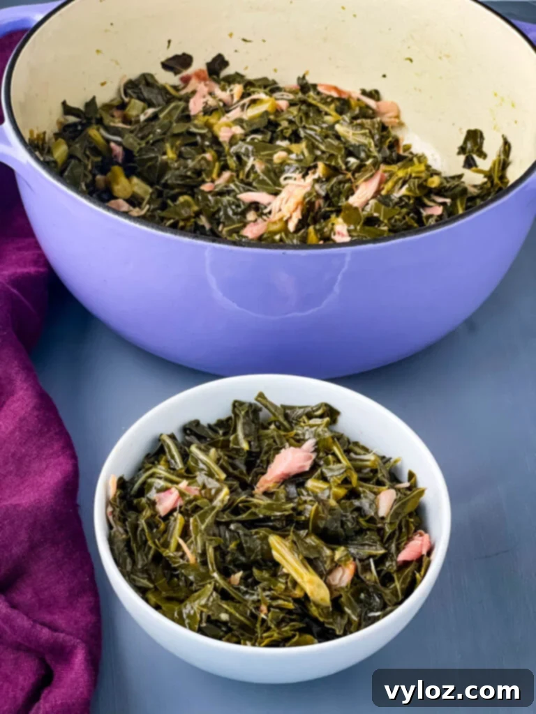 Southern collard greens served in a white bowl with a purple pot in the background.