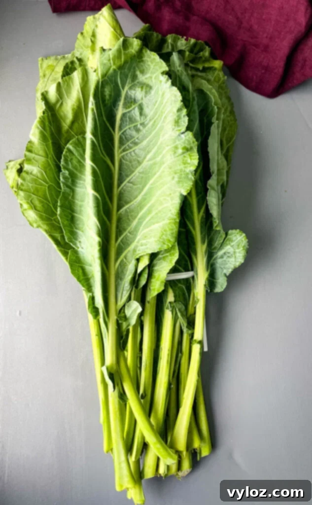 A pile of fresh collard greens on a flat surface, ready for preparation.