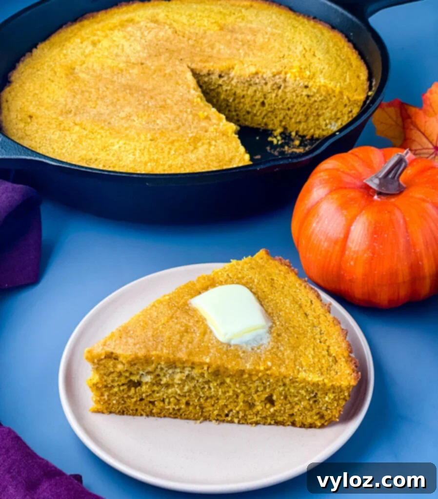 Delicious pumpkin cornbread on a plate, with more cornbread visible in a rustic cast iron skillet