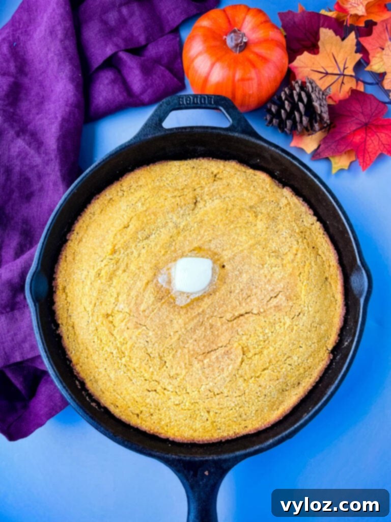 Freshly baked pumpkin cornbread in a cast iron skillet, golden brown and ready to be served