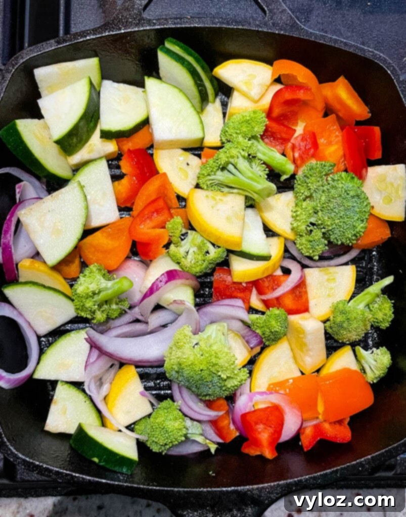 Fresh vegetables, including bell peppers, zucchini, and broccoli, arranged on a grill rack
