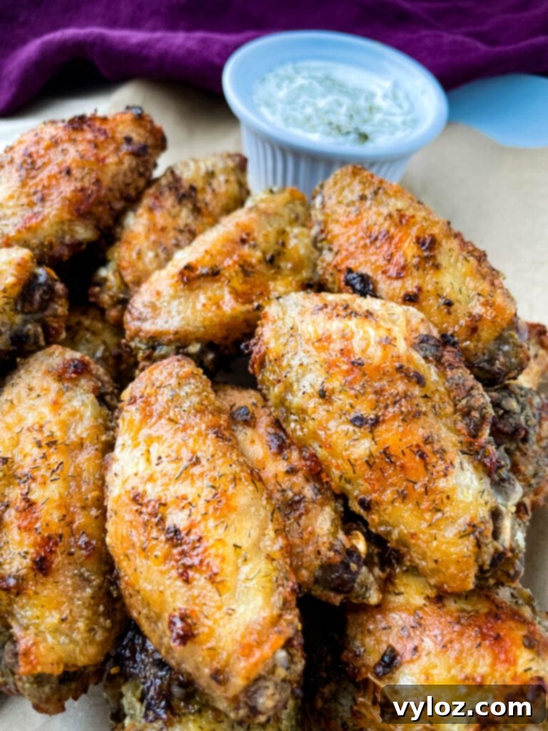 Crispy ranch chicken wings arranged on a plate with a side of ranch dipping sauce, garnished with fresh herbs.